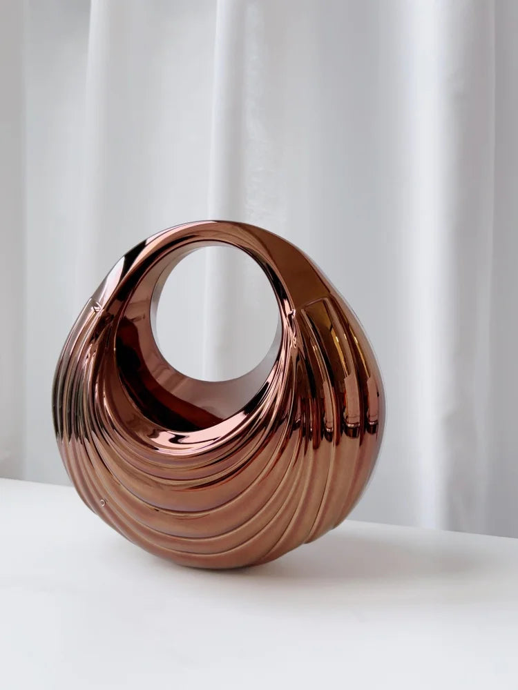 תיק ערב עגול מטאלי עם גלים מפוסלים וידית חלולה – נחושת